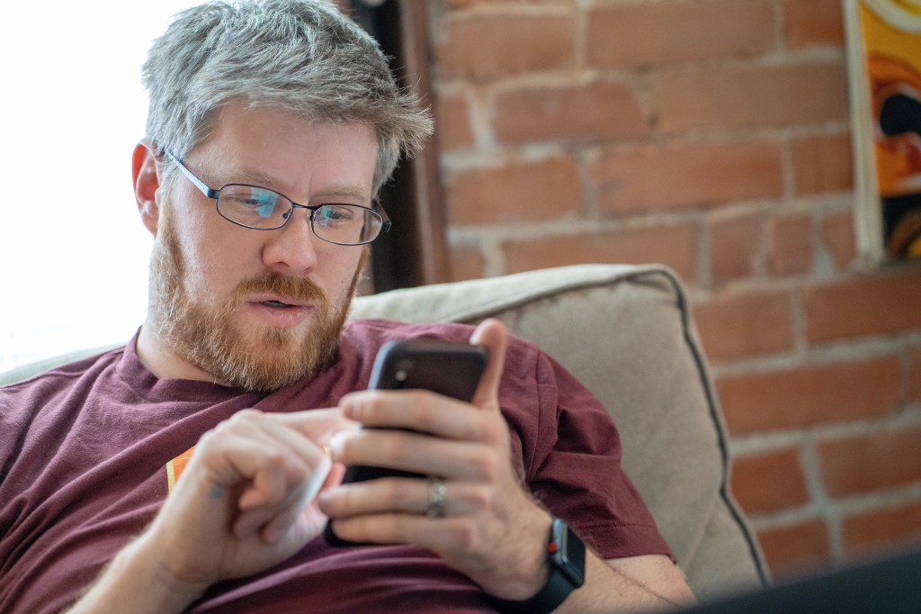 Greg Brown looking at his phone on a couch