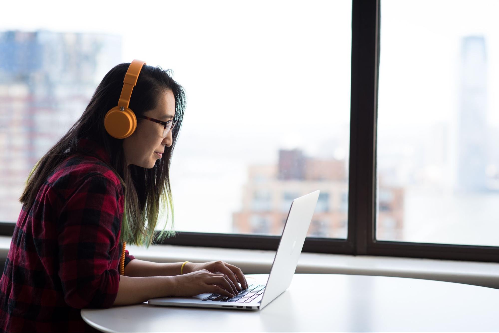 woman working on a laptop, wearing headphones