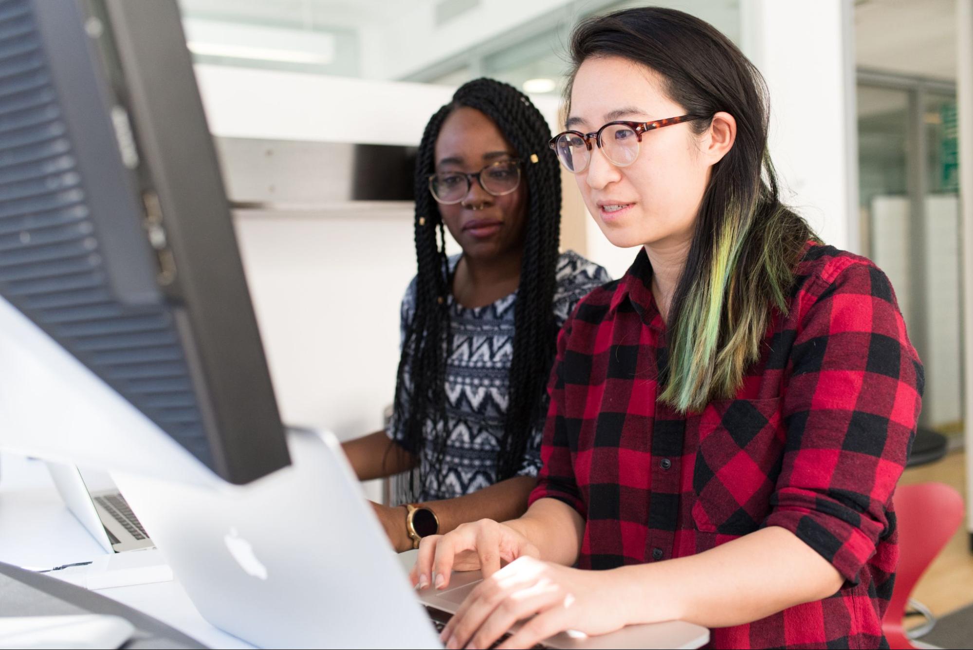two female developers working on a desktop computer