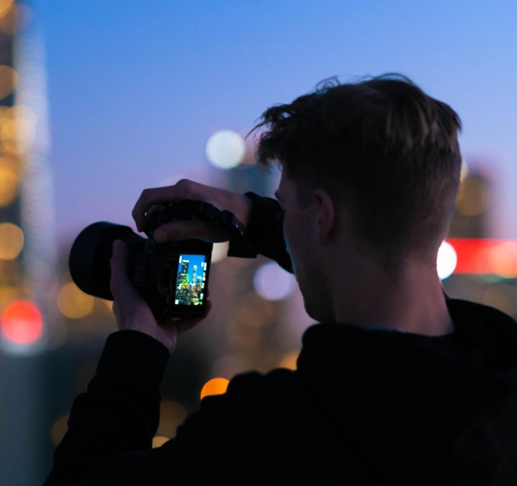 man taking a photo of a city at night