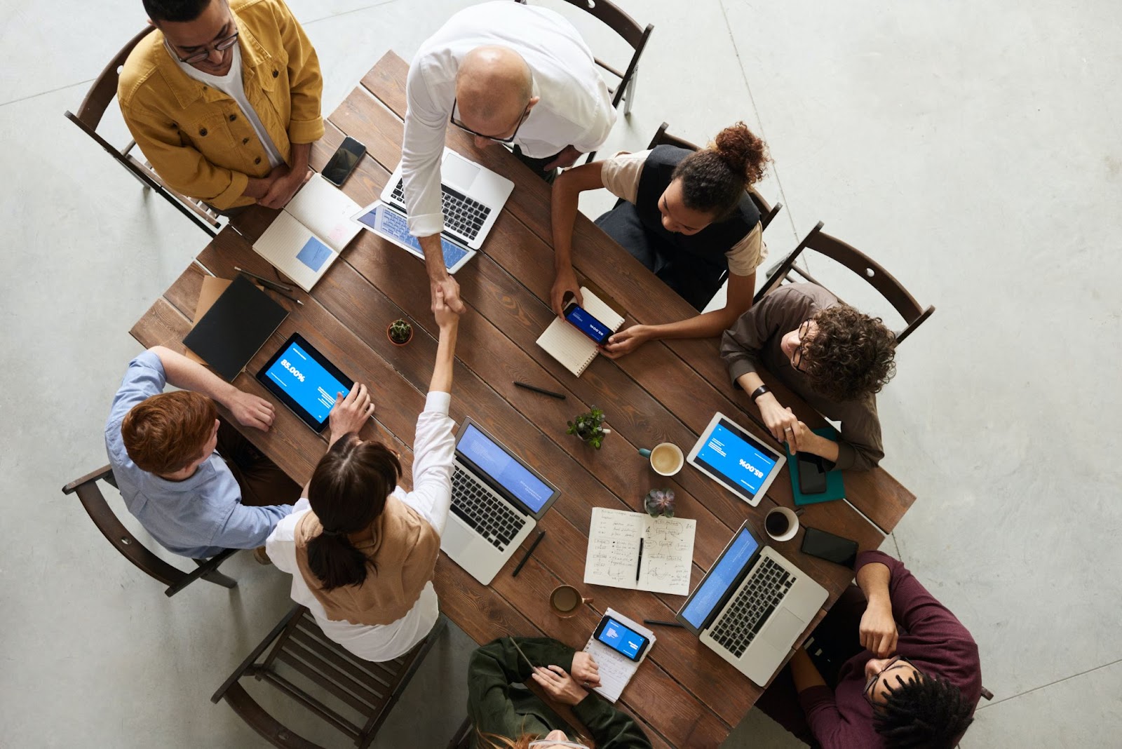 team members meeting around a table with various devices