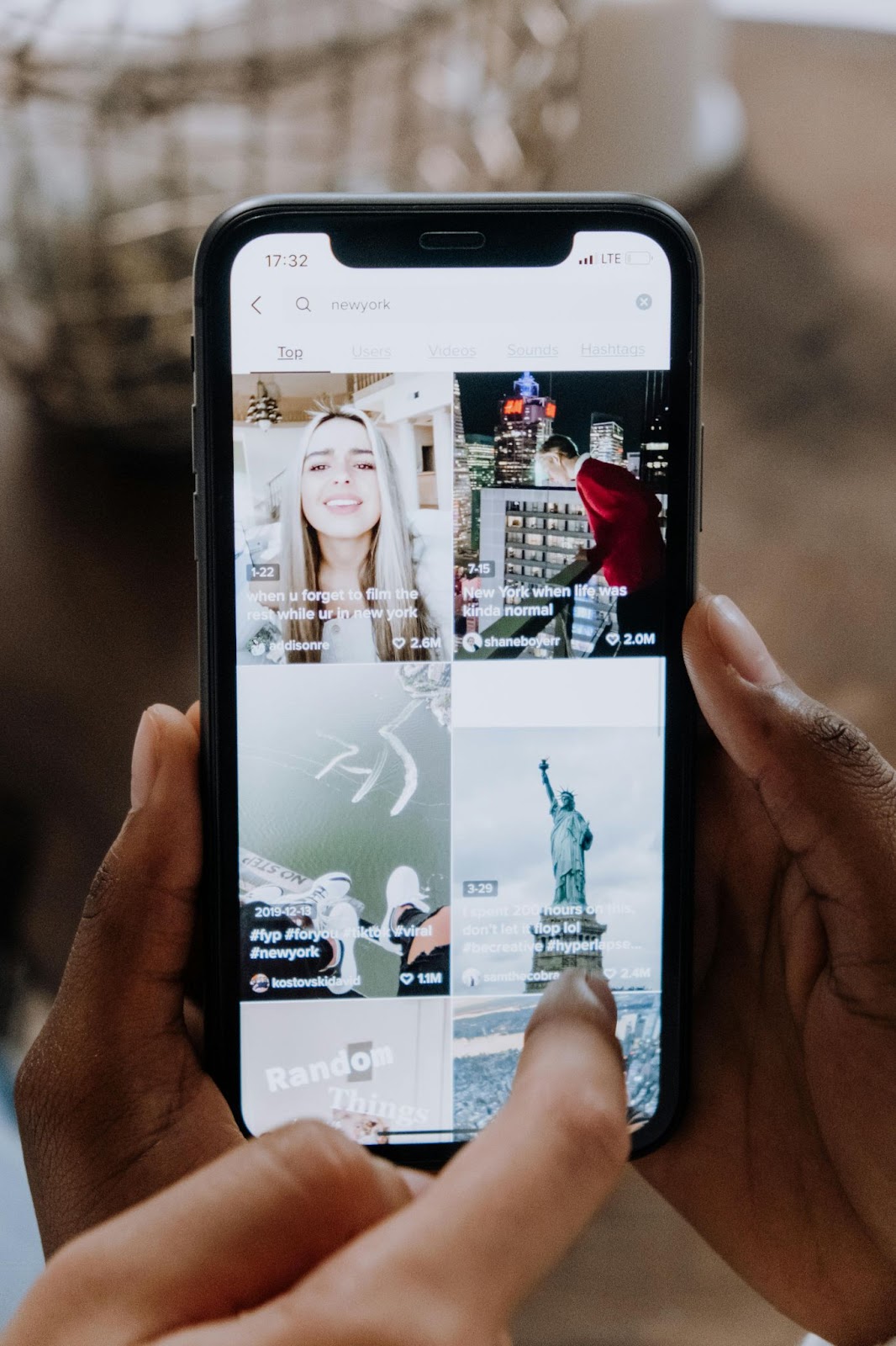 Two sets of hands holding and point at a social media application on a smart phone.