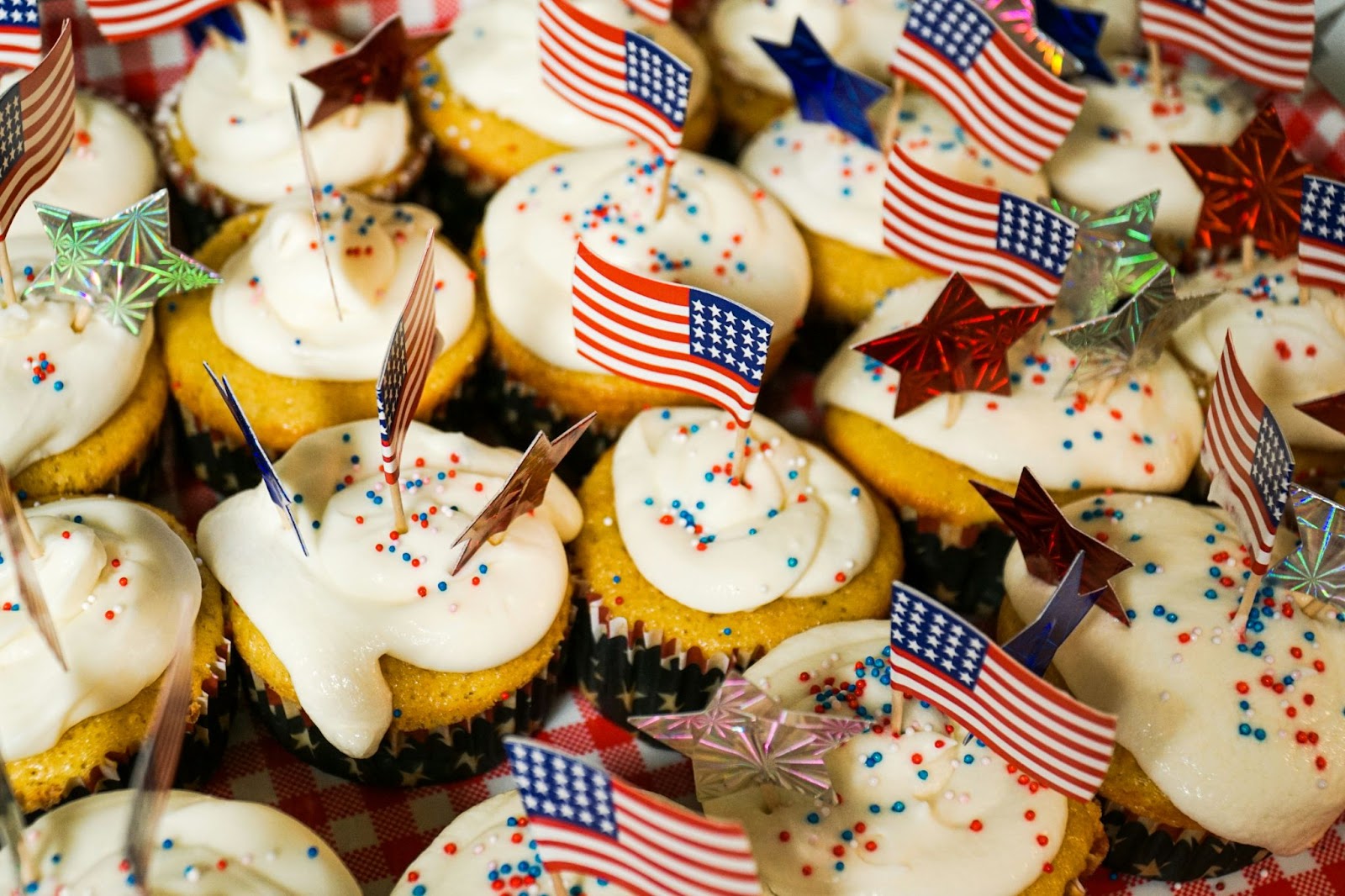 White cupcakes with white icing and red, white, and blue sprinkles, little American flags and stars sticking out from the top of each.