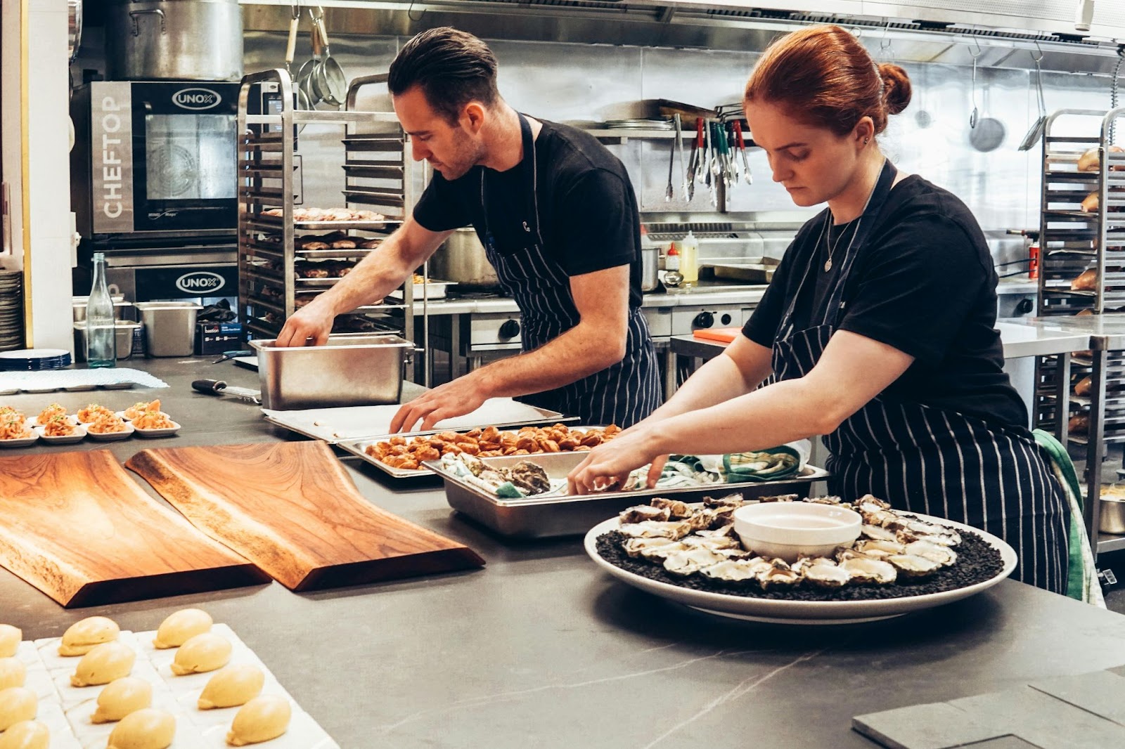Two chefs preparing trays of food for what appears to be a large party or some sort of event.