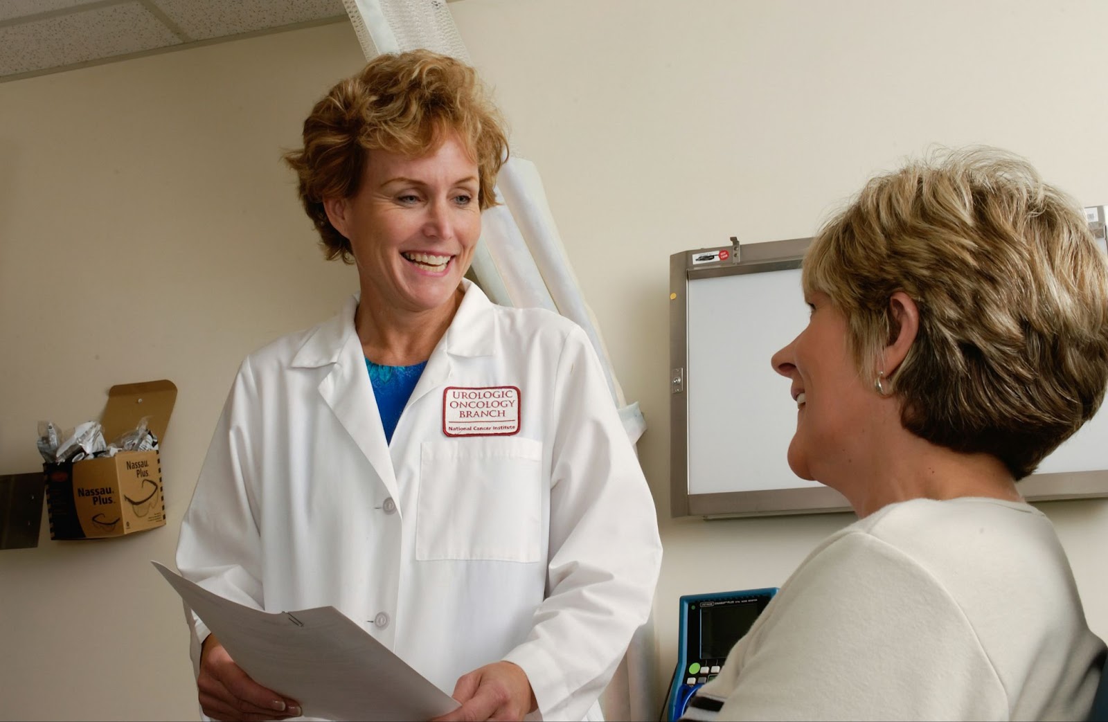 An oncologist give what appears to be positive to news to her patient.  They are both smiling.