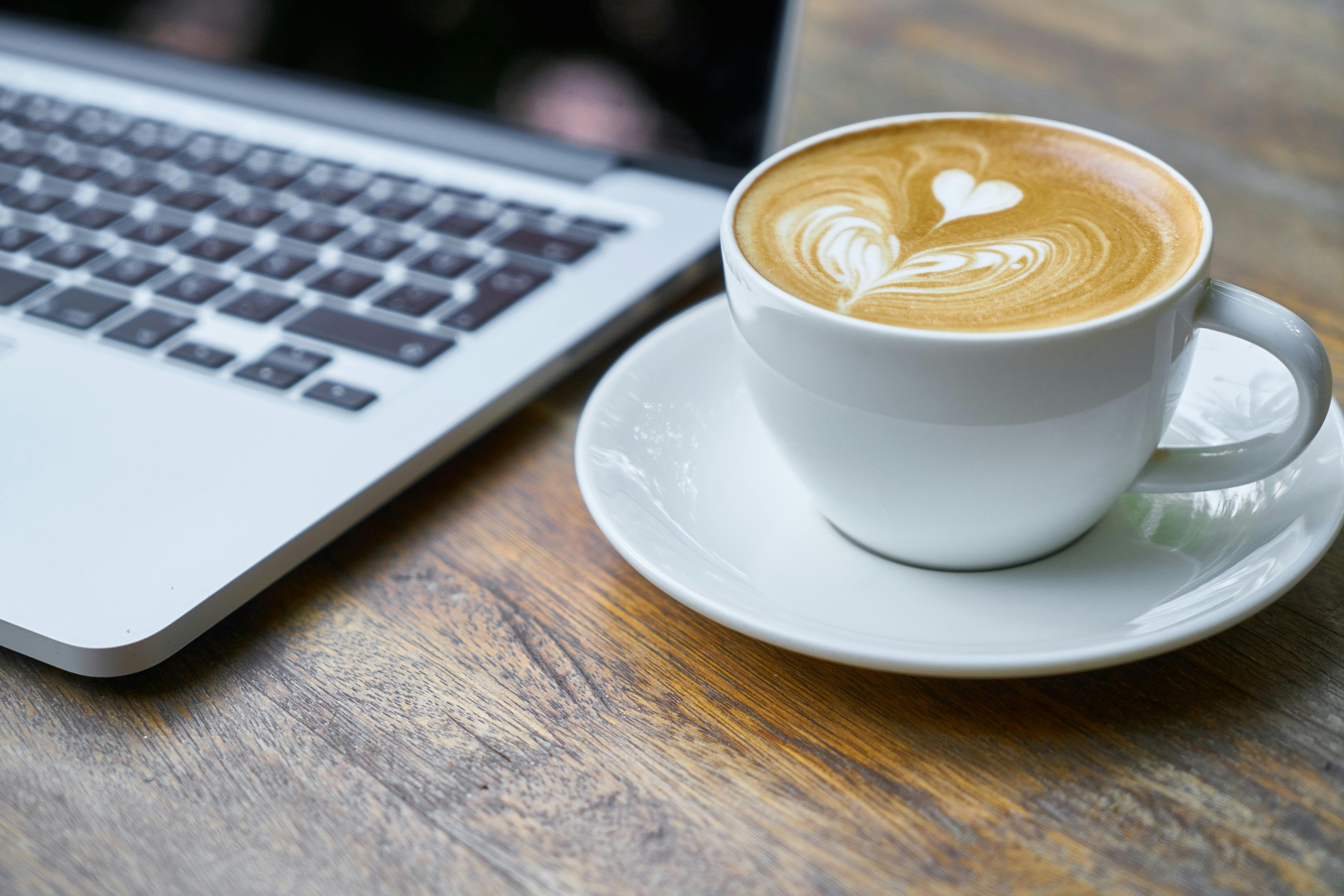 cup of coffee next to a laptop