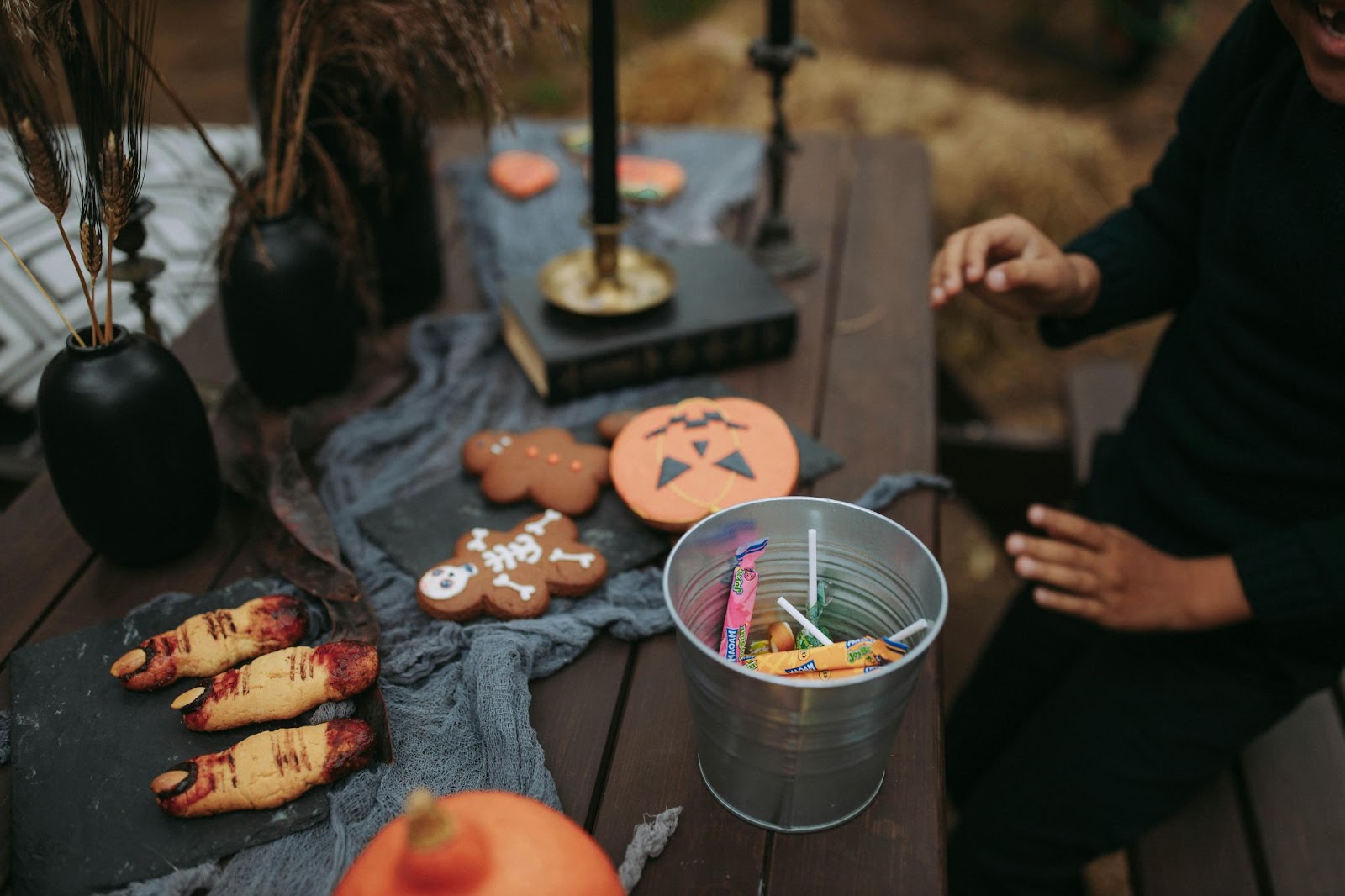 Halloween themed cookies being decorated in a rustic, barn-like outdoor space. 