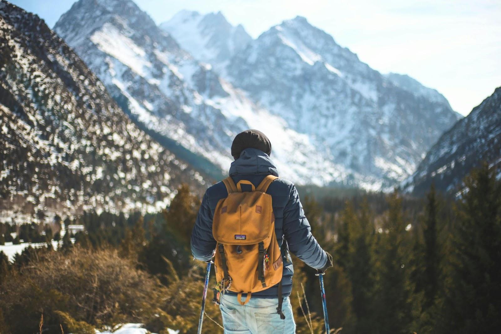 someone hiking in the mountains, wearing a coat and backpack