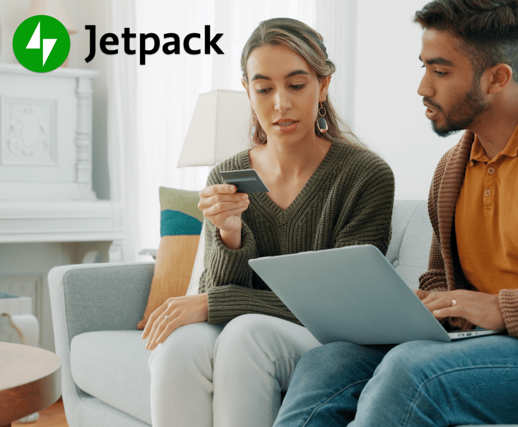 two people sitting on a cough purchasing something on a laptop