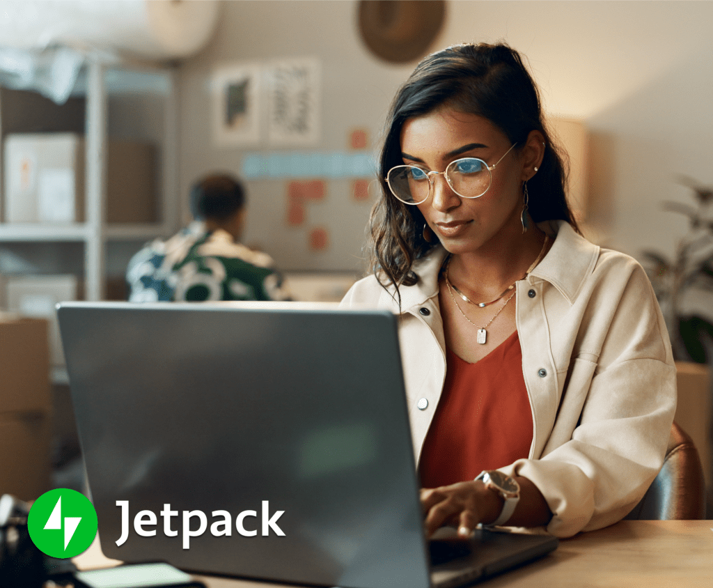 A woman working on her laptop in a warmly lit office.