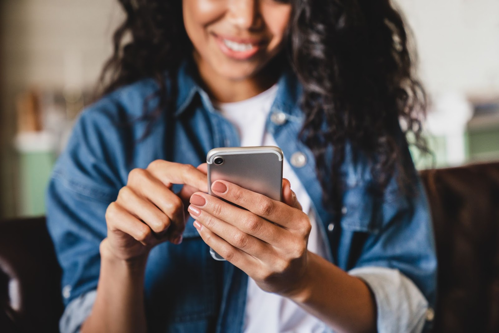 Girl smiling at her as she looks happily at her phone. 
