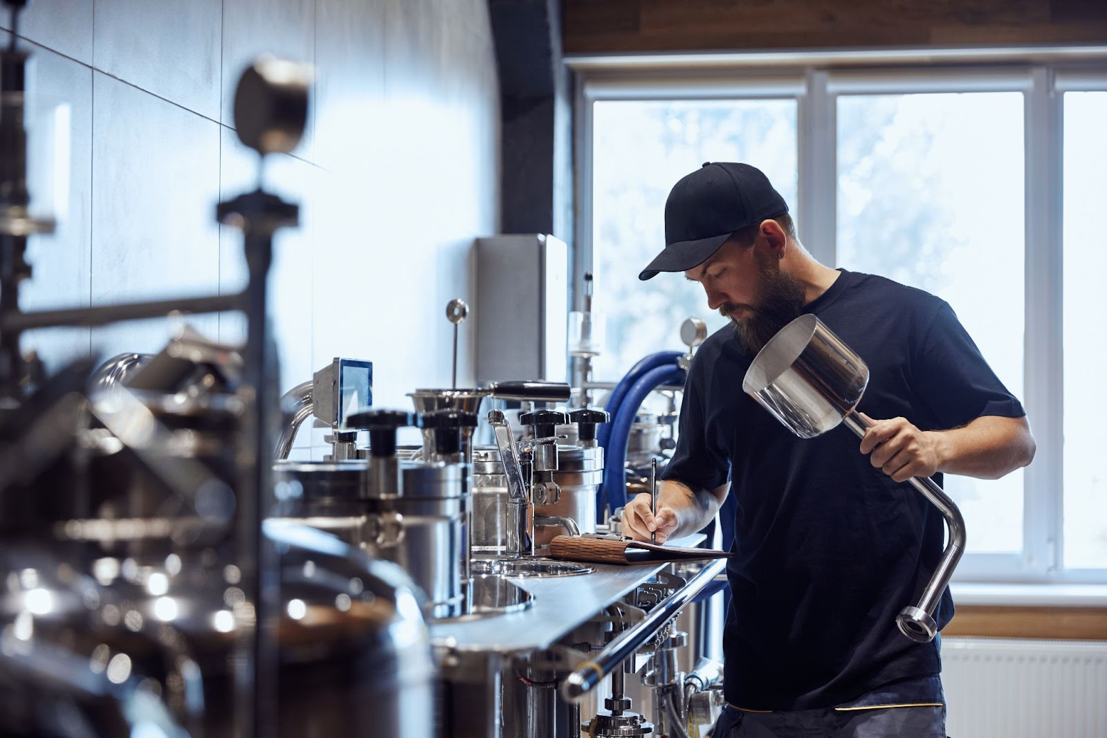 Man working with stainless steal tools, taking notes on what is accomplishing. 