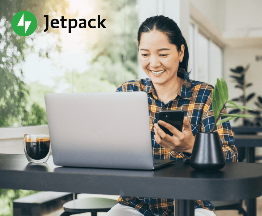 Woman working on her laptop in an office with natural light and a lot of plants.