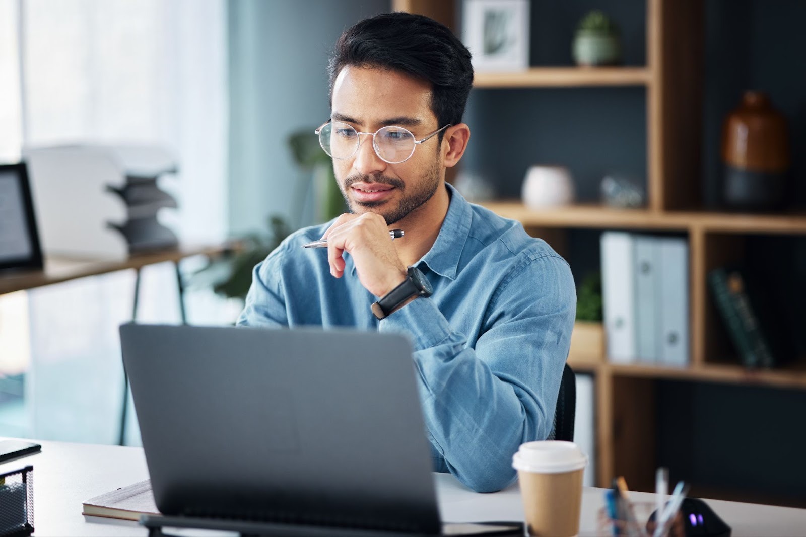 Man working on his laptop in an office with a lot of natural light.