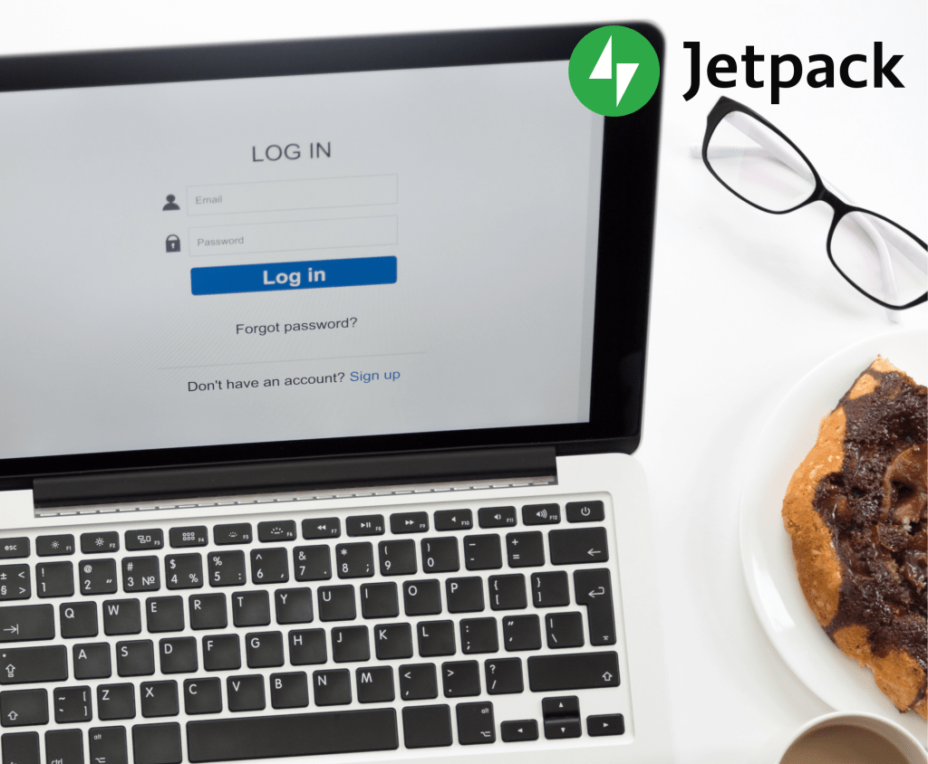 A desk with a pair of glasses, a pastry, and a computer displaying a login screen.