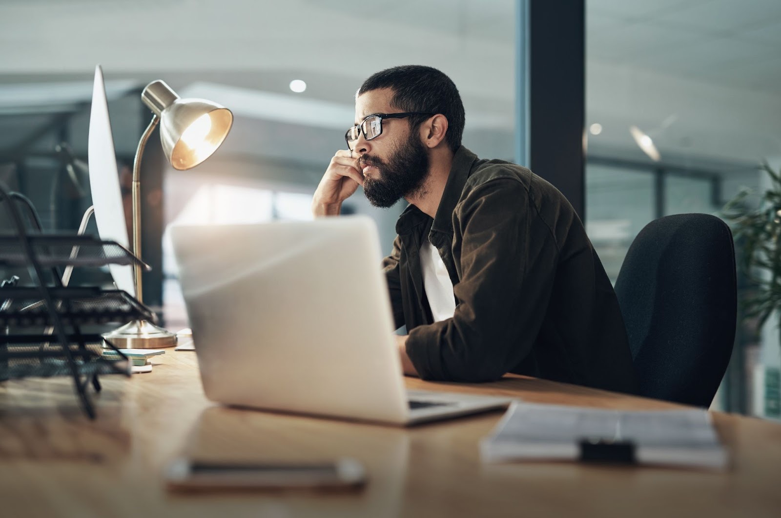 Man working at his desk with multiple trying to solve some sort of problem.