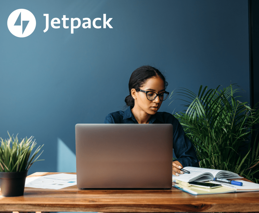 woman working on a computer in front of a dark blue wall
